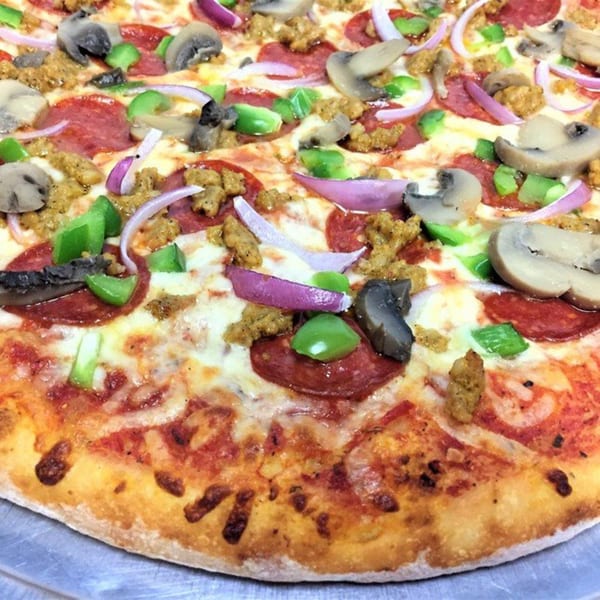 Close-up of a pizza with pepperoni, sausage, mushrooms, green peppers, and red onions.