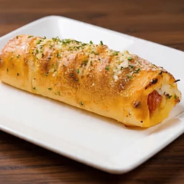 Golden-baked stromboli with melted cheese and pepperoni, garnished with herbs, on a white plate.